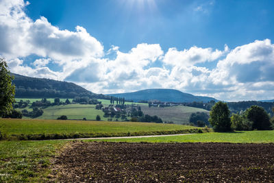 Scenic view of agricultural field against cloudy sky