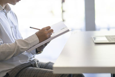 Midsection of man working on table