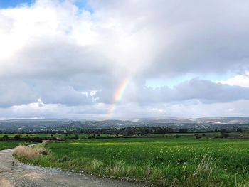 Scenic view of rainbow over land against sky