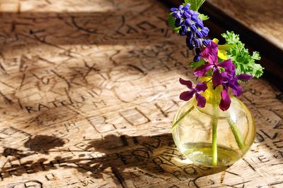 High angle view of flowers in glass vase on scribbled table