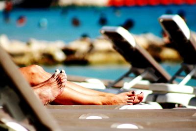 Low section of women relaxing on deck chairs at beach