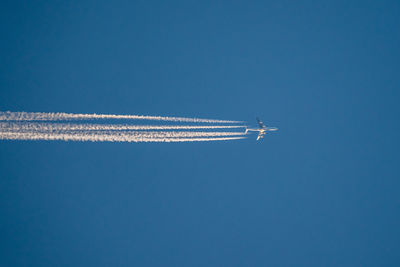 Low angle view of airplane flying against clear blue sky