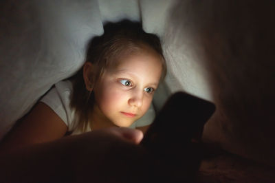 Girl using mobile while lying on bed