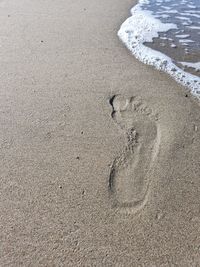 High angle view of footprints on wet sand