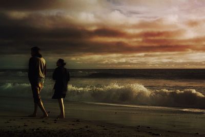 People walking on beach at sunset