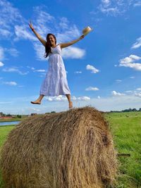 Rear view of woman jumping on field against sky