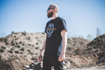 Young man wearing sunglasses standing on land