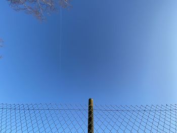 Barbed wire fence against clear blue sky