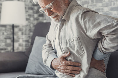 Low angle view of man sitting on sofa at home