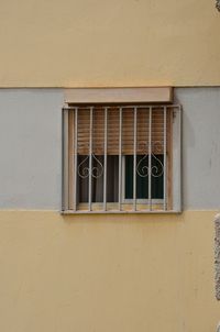 Barred window on yellow building wall