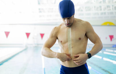 Rear view of shirtless man standing against wall