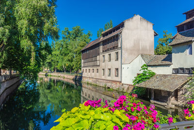 Canal amidst buildings and trees against sky