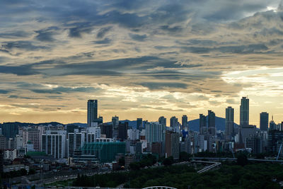 Modern buildings in city against sky during sunset