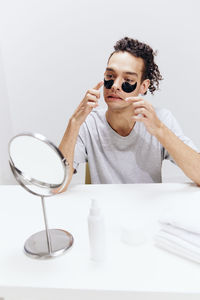 Portrait of young woman wearing sunglasses against white background