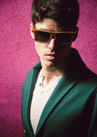 Portrait of man wearing sunglasses against pink wall