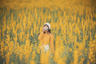 Young woman photographing on field