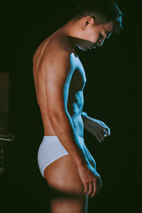 Rear view of woman standing against black background