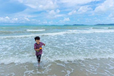 Full length of boy on beach against sky