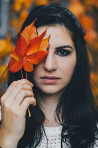 Close-up of young woman with autumn leaves