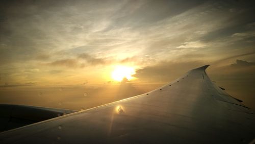 Close-up of airplane wing against sky during sunset