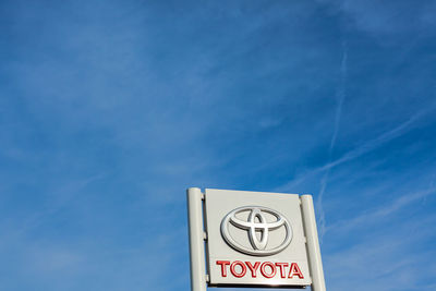 Low angle view of road sign against blue sky