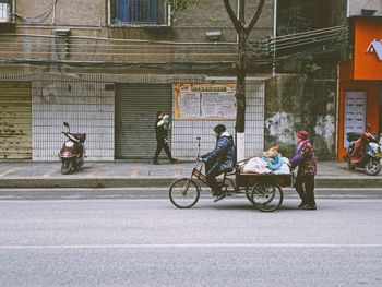 People sitting on road against building