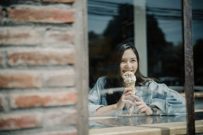 Smiling young woman holding ice cream in store