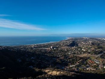 Aerial view of town by sea against blue sky