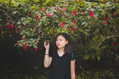 Beautiful young woman with red flowers in autumn leaves