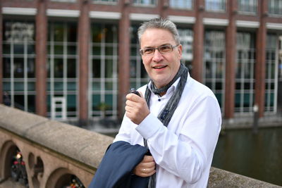 Businessman holding smoking pipe while standing against building 