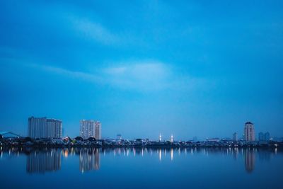 Scenic view of lake by buildings against blue sky