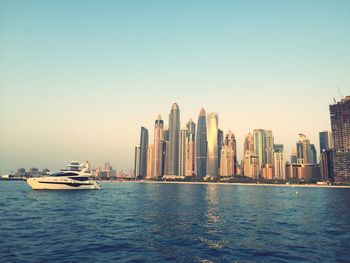 Sea and modern buildings in city against clear sky