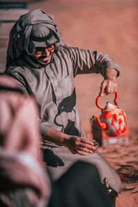 Man wearing traditional clothing pouring tea in cup