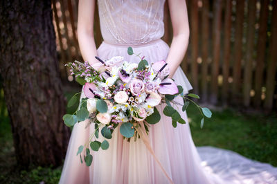 Midsection of woman standing by flowers