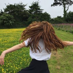 Rear view of woman standing on grassy field