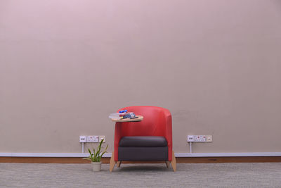 Empty chair on with books against wall at home