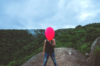 Rear view of woman standing on mountain against sky