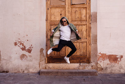 Full length portrait of man jumping against wall