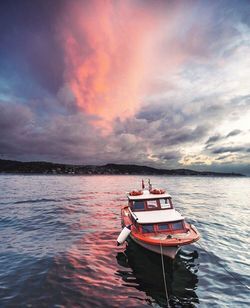 Boats in sea against cloudy sky