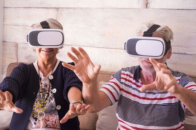Senior couple wearing virtual reality simulator against wall