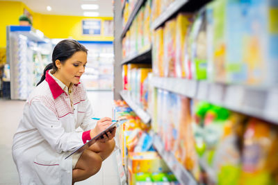 Full length of woman using mobile phone in store