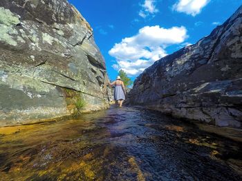 Woman wading in sea amidst rock formations