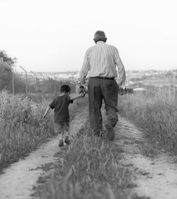 Rear view of father and son walking on field