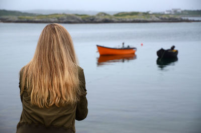 Rear view of woman with blond long hair by lake