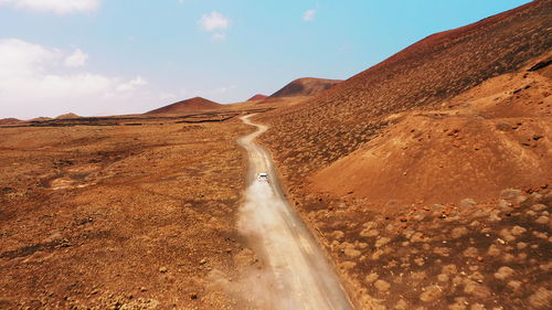 Car driving on empty dirt road in desert volcanic landscape at summer sunny day. fuerteventura.