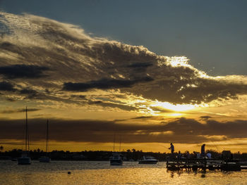 Silhouette boats sailing in sea against sky during sunset