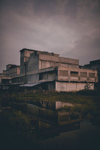 Buildings by river against sky