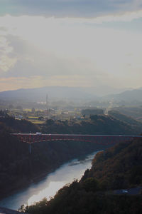 Bridge over river by city against sky