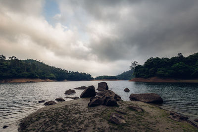 Rocks by lake against sky