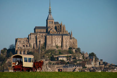 Horse carriage and castle against blue sky